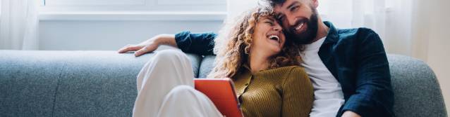 Pärchen sitzt lachend auf Couch